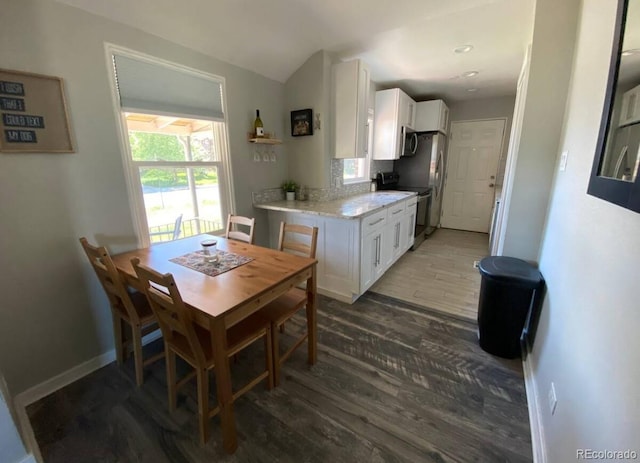 dining space with vaulted ceiling and dark wood-type flooring