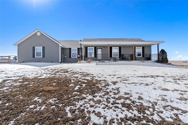 snow covered back of property featuring covered porch