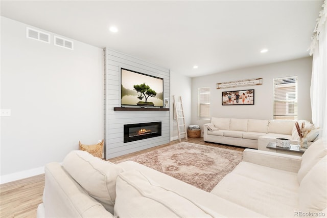 living room featuring light wood-type flooring and a large fireplace