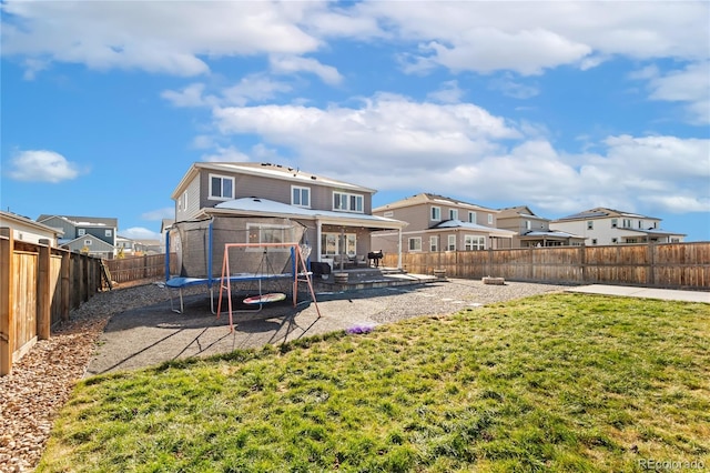 rear view of property with a lawn, a patio area, and a trampoline