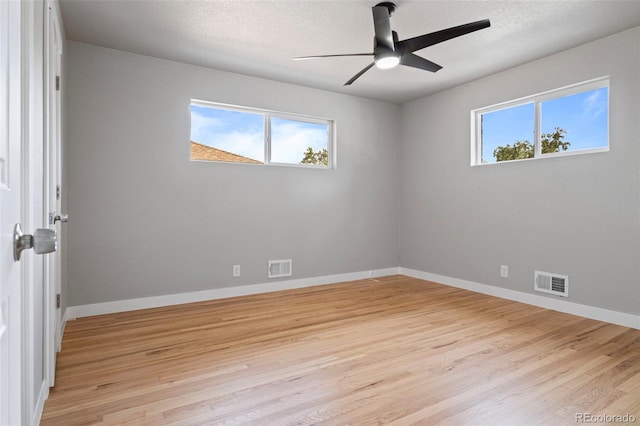 spare room featuring plenty of natural light, a textured ceiling, and light wood-type flooring