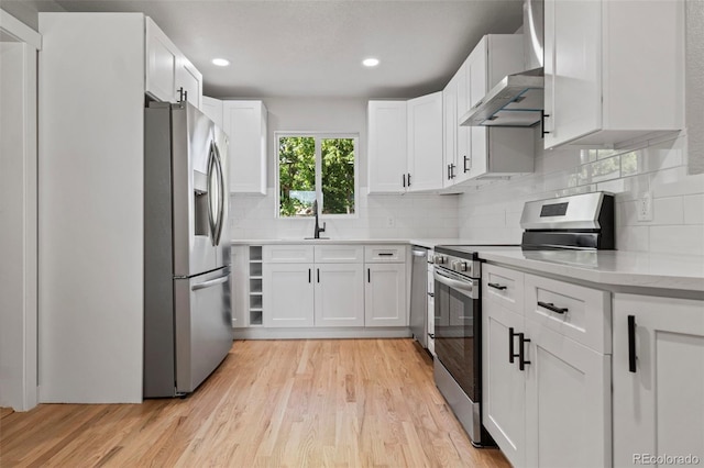 kitchen with stainless steel appliances, backsplash, white cabinets, and light hardwood / wood-style floors