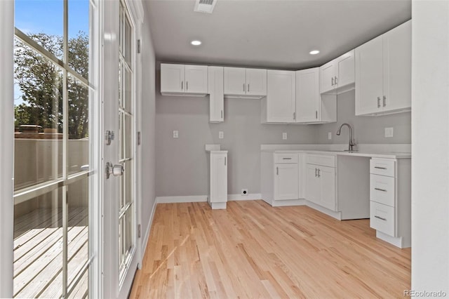 kitchen with white cabinetry, sink, and light wood-type flooring