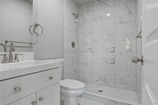 bathroom featuring vanity, toilet, and a tile shower