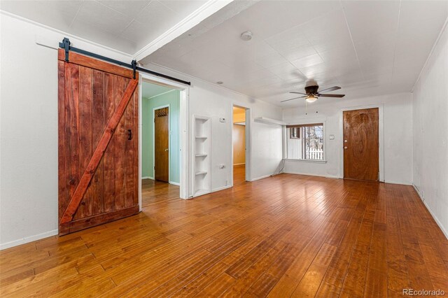 2515 Ames St, Edgewater, CO 80214 - unfurnished living room featuring a ceiling fan, wood finished floors, built in features, a barn door, and baseboards