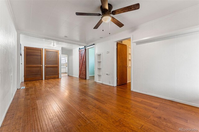 2515 Ames St, Edgewater, CO 80214 - unfurnished bedroom with a barn door, hardwood / wood-style floors, and baseboards