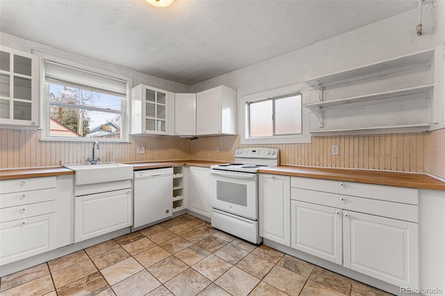 2515 Ames St, Edgewater, CO 80214 - kitchen with white appliances, a sink, healthy amount of natural light, white cabinetry, and wood walls