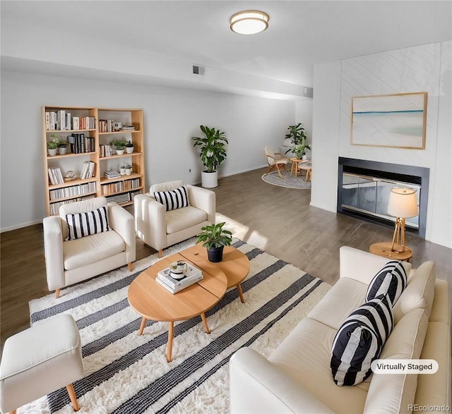 living room featuring a large fireplace and dark wood-type flooring