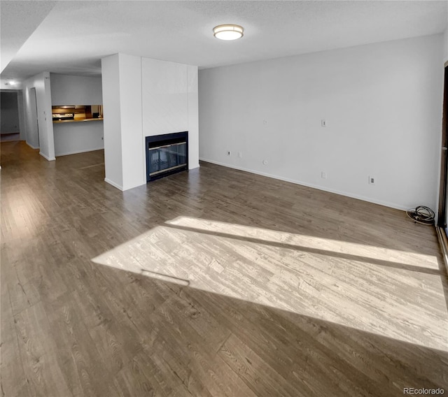 unfurnished living room with a large fireplace, a textured ceiling, and wood-type flooring