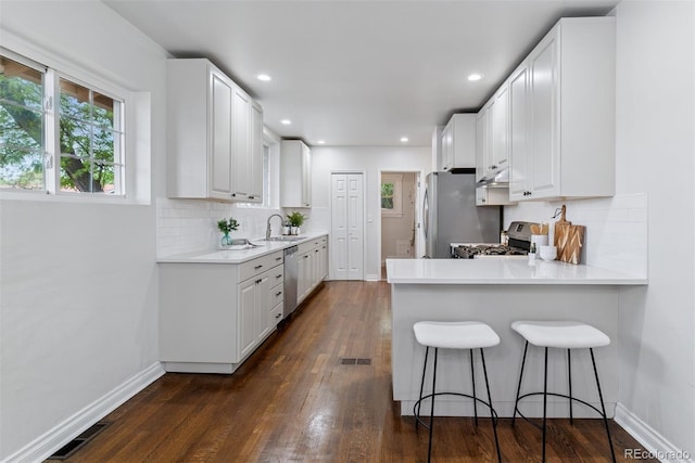 4003 Federal Blvd, Denver, CO 80211 - kitchen featuring stainless steel appliances, a sink, white cabinetry, backsplash, and a kitchen breakfast bar