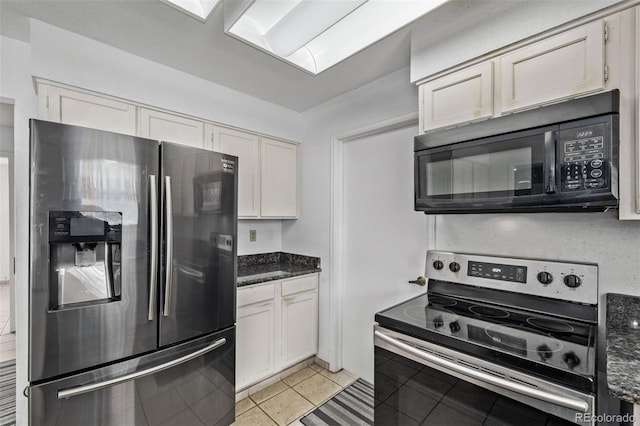 kitchen featuring white cabinetry, appliances with stainless steel finishes, dark stone countertops, and light tile patterned floors