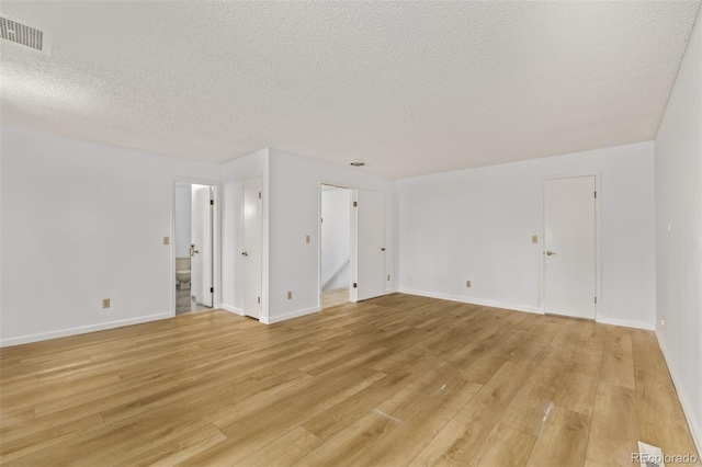 empty room with light hardwood / wood-style floors and a textured ceiling