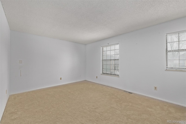 carpeted empty room featuring a textured ceiling