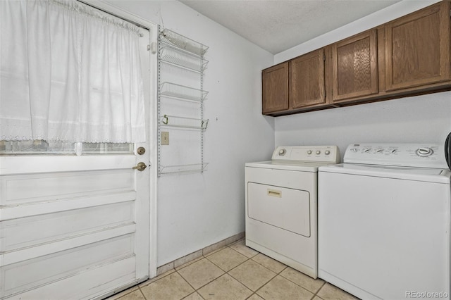 laundry room featuring light tile patterned flooring, cabinets, washer and dryer, and a textured ceiling