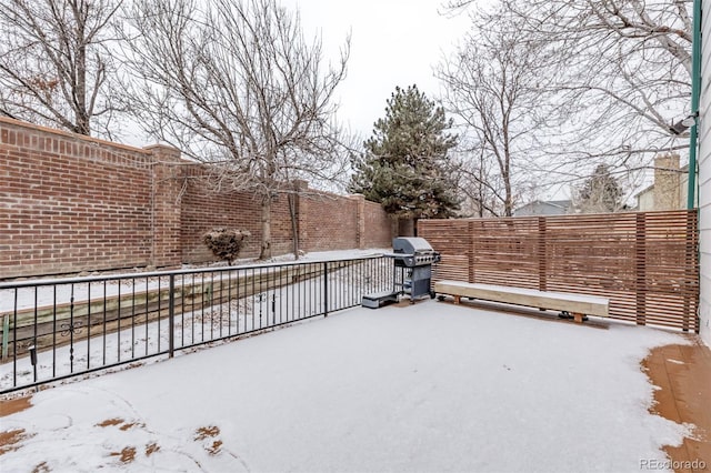 yard layered in snow with fence and a patio area