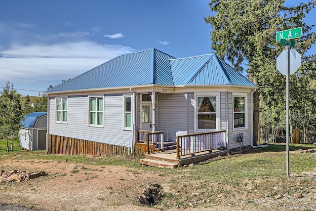 view of front facade featuring a storage shed, a deck, and a front yard