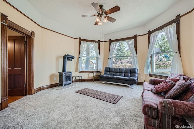 carpeted living room with ceiling fan, a wood stove, and a textured ceiling