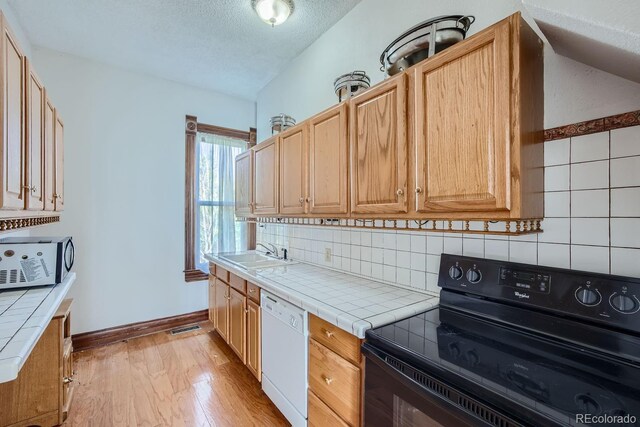 kitchen with light wood-type flooring, tile countertops, black electric range, and white dishwasher