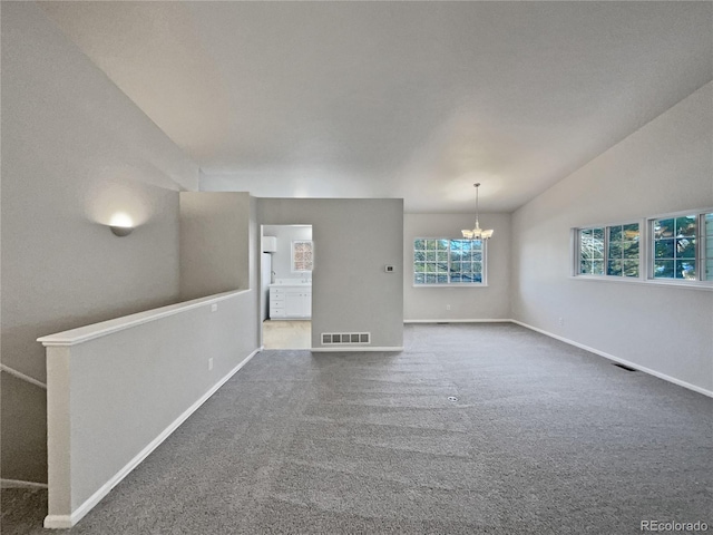 carpeted empty room featuring lofted ceiling and a notable chandelier