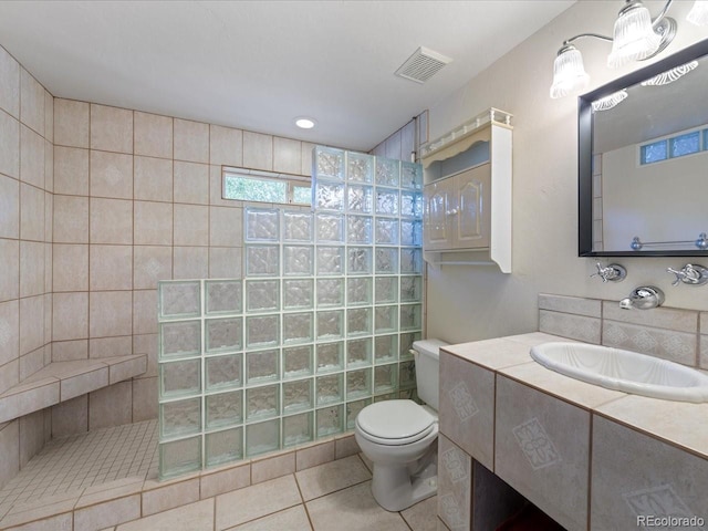 bathroom with tile patterned floors, toilet, a tile shower, and vanity