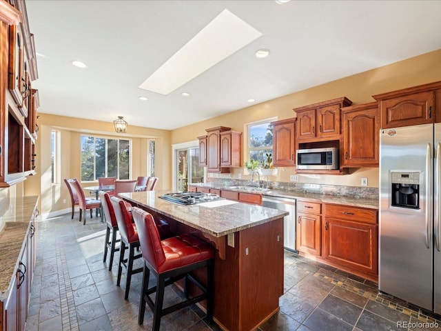 kitchen with appliances with stainless steel finishes, a healthy amount of sunlight, a kitchen island, and a skylight