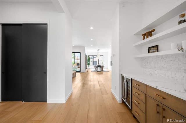 hallway with light wood finished floors, wine cooler, baseboards, and recessed lighting