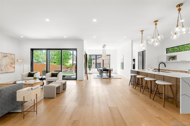 living area featuring light wood-type flooring, recessed lighting, a chandelier, and baseboards