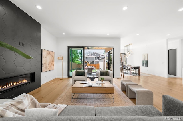 living room with wood finished floors, a large fireplace, recessed lighting, baseboards, and a chandelier
