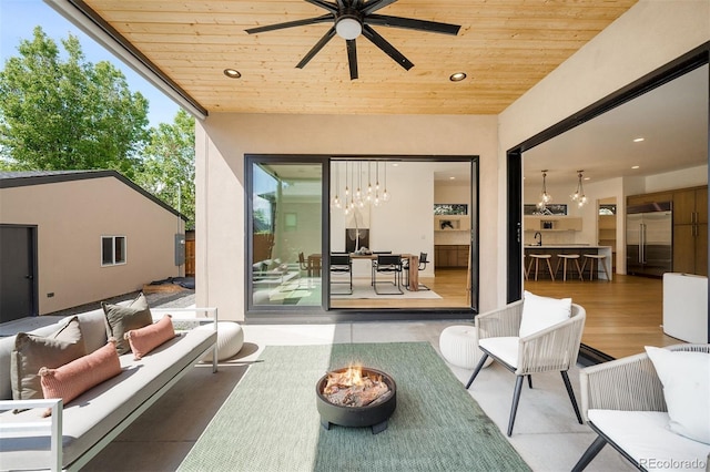 view of patio with an outdoor living space with a fire pit and a ceiling fan