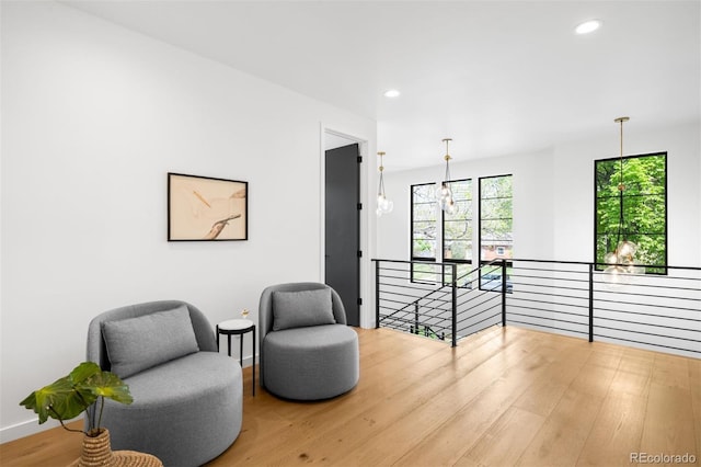 sitting room with an upstairs landing, wood finished floors, recessed lighting, and baseboards