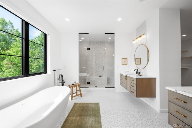 bathroom featuring vanity, a shower stall, a soaking tub, recessed lighting, and baseboards
