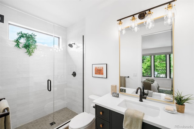 ensuite bathroom featuring healthy amount of natural light, a stall shower, vanity, and toilet