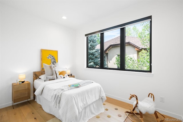 bedroom with light wood-style floors, baseboards, and recessed lighting