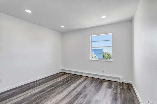 spare room featuring a baseboard radiator, baseboards, wood finished floors, and recessed lighting