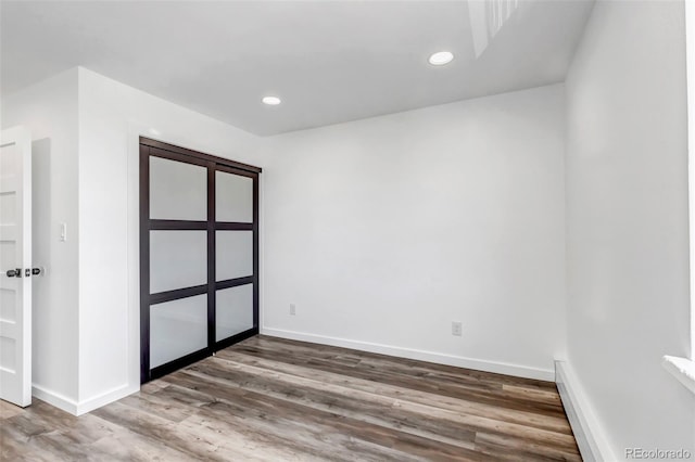 unfurnished room with recessed lighting, wood finished floors, and baseboards