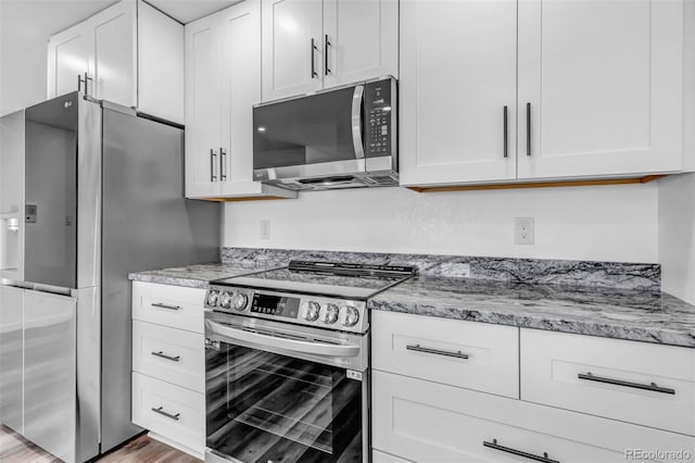 kitchen with appliances with stainless steel finishes, white cabinets, and light stone countertops