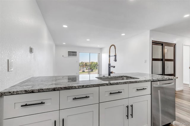 kitchen featuring white cabinets, light wood-style flooring, a sink, light stone countertops, and stainless steel dishwasher