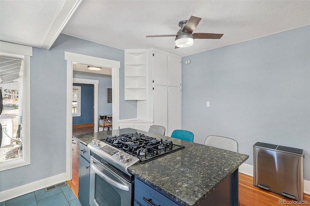 4196 S Pennsylvania St, Englewood, CO 80113 - kitchen featuring visible vents, stainless steel gas stove, baseboards, a ceiling fan, and dark stone countertops