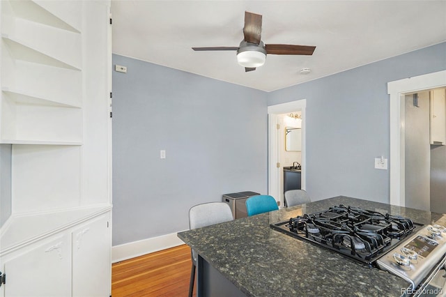 4196 S Pennsylvania St, Englewood, CO 80113 - kitchen with light wood finished floors, stove, dark stone countertops, a ceiling fan, and baseboards