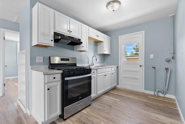 10911 W 44th Pl, Wheat Ridge, CO 80033 - kitchen with stainless steel range with gas stovetop, under cabinet range hood, light wood-style floors, light countertops, and white cabinets