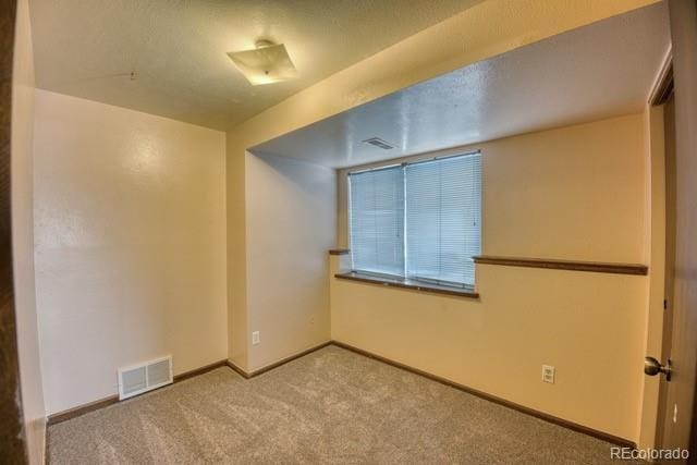 unfurnished room with baseboards, visible vents, and carpet flooring