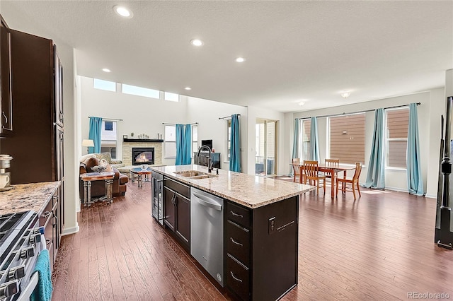 6335 E 143rd Dr, Thornton, CO 80602 - kitchen with stainless steel appliances, open floor plan, a stone fireplace, dark wood-type flooring, and plenty of natural light