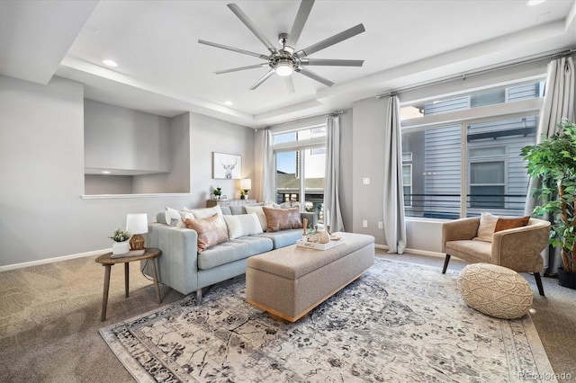 living room with ceiling fan, a tray ceiling, and carpet