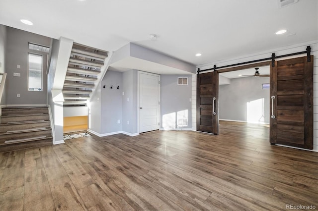 unfurnished living room with hardwood / wood-style flooring and a barn door