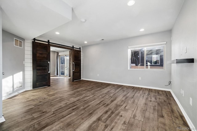 unfurnished living room with wood-type flooring and a barn door