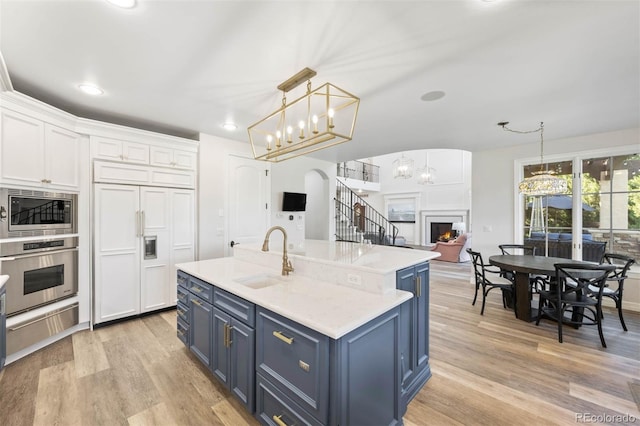9151 E Harvard Ave, Denver, CO 80231 - kitchen featuring built in appliances, blue cabinets, a warming drawer, white cabinets, and light wood finished floors