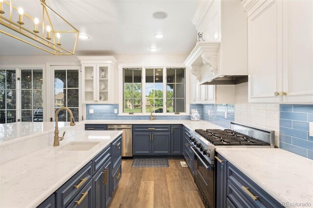 9151 E Harvard Ave, Denver, CO 80231 - kitchen with appliances with stainless steel finishes, white cabinets, wood finished floors, light stone counters, and hanging light fixtures