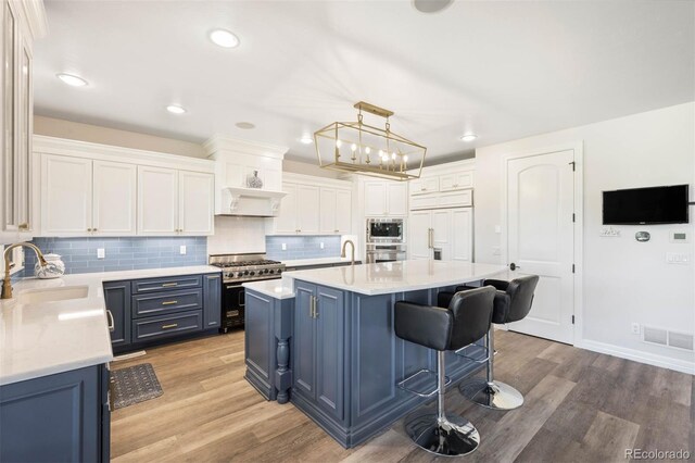 9151 E Harvard Ave, Denver, CO 80231 - kitchen featuring built in appliances, blue cabinetry, light wood finished floors, light countertops, and recessed lighting
