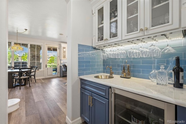9151 E Harvard Ave, Denver, CO 80231 - indoor wet bar featuring wine cooler, wood finished floors, backsplash, and decorative light fixtures
