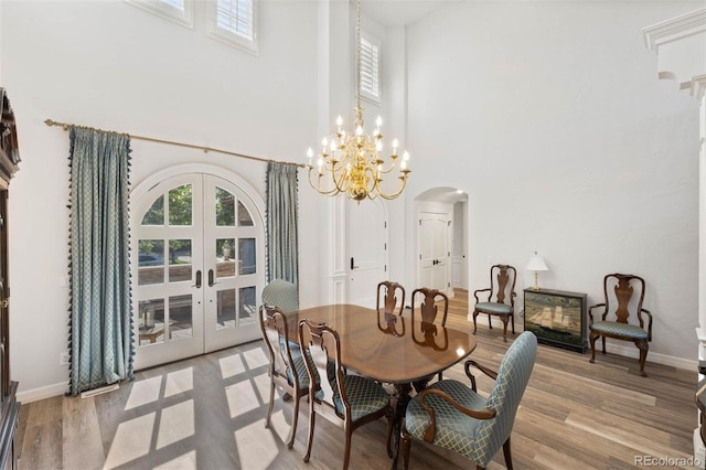 9151 E Harvard Ave, Denver, CO 80231 - dining space with arched walkways, a towering ceiling, french doors, light wood finished floors, and a chandelier